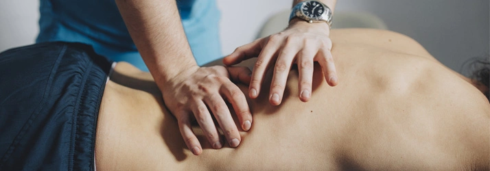 Practitioner performing manual back therapy, applying precise pressure along the spine.